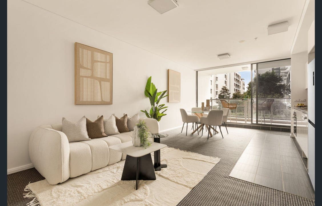 Bright open-plan living and dining area styled by RitZi Stagings with a cream sofa and glass dining table.